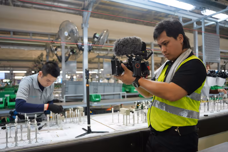 Profissional filmando um trabalhador em uma linha de produção industrial
